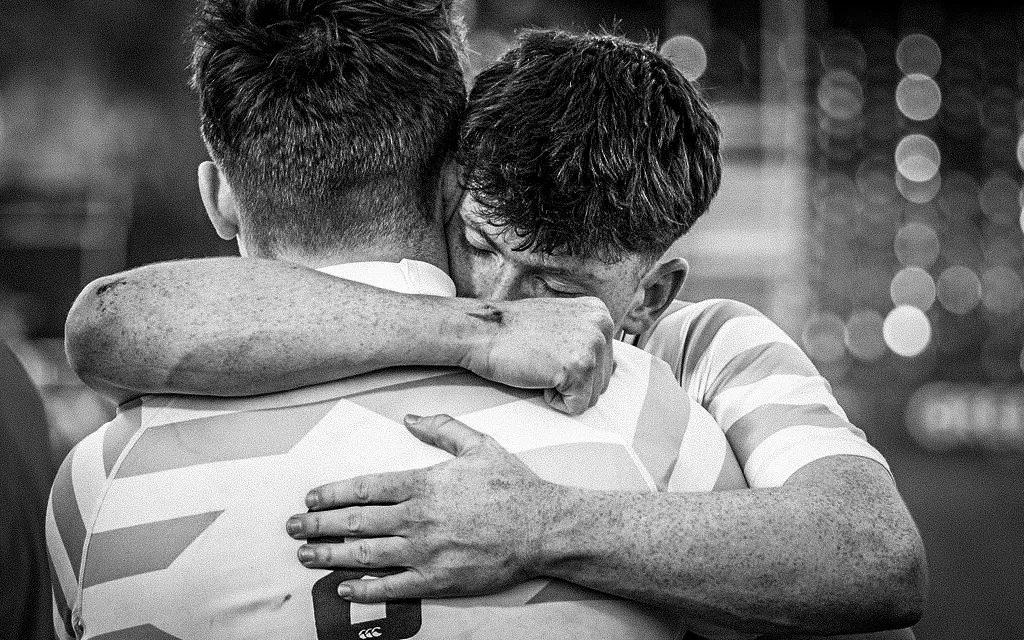 Two male rugby players hugging each other.