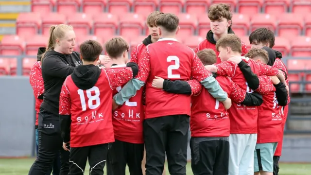 mentoring teenage boys in a huddle as they talk to a teacher about rugby 